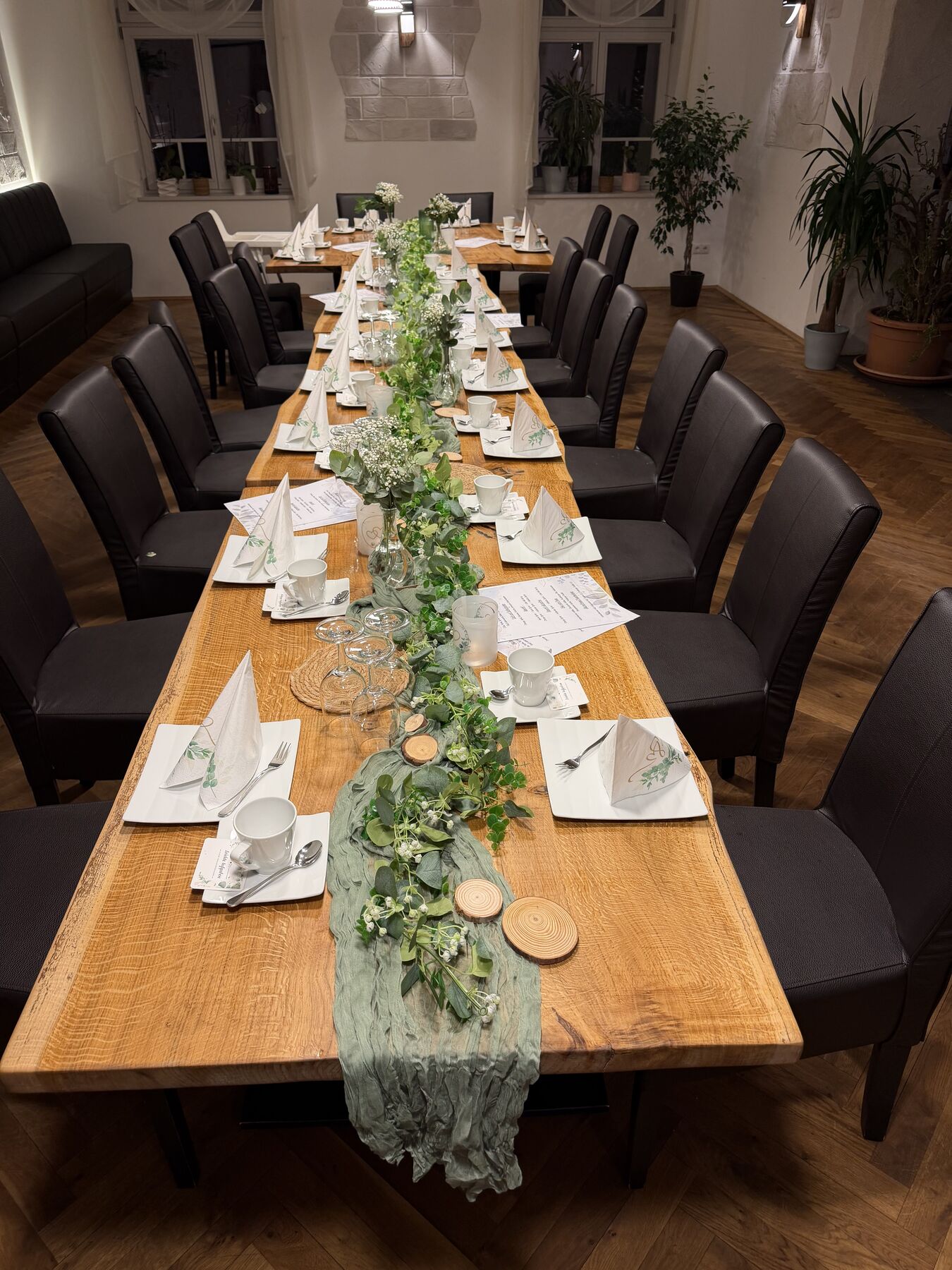 Lange Tafel im Gastraum mit grüner Girlande