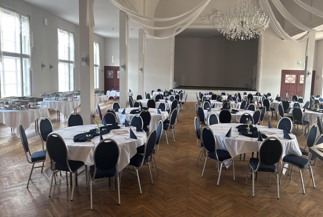 Saal mit runden Tischen, an der Seite ist das Buffet aufgebaut