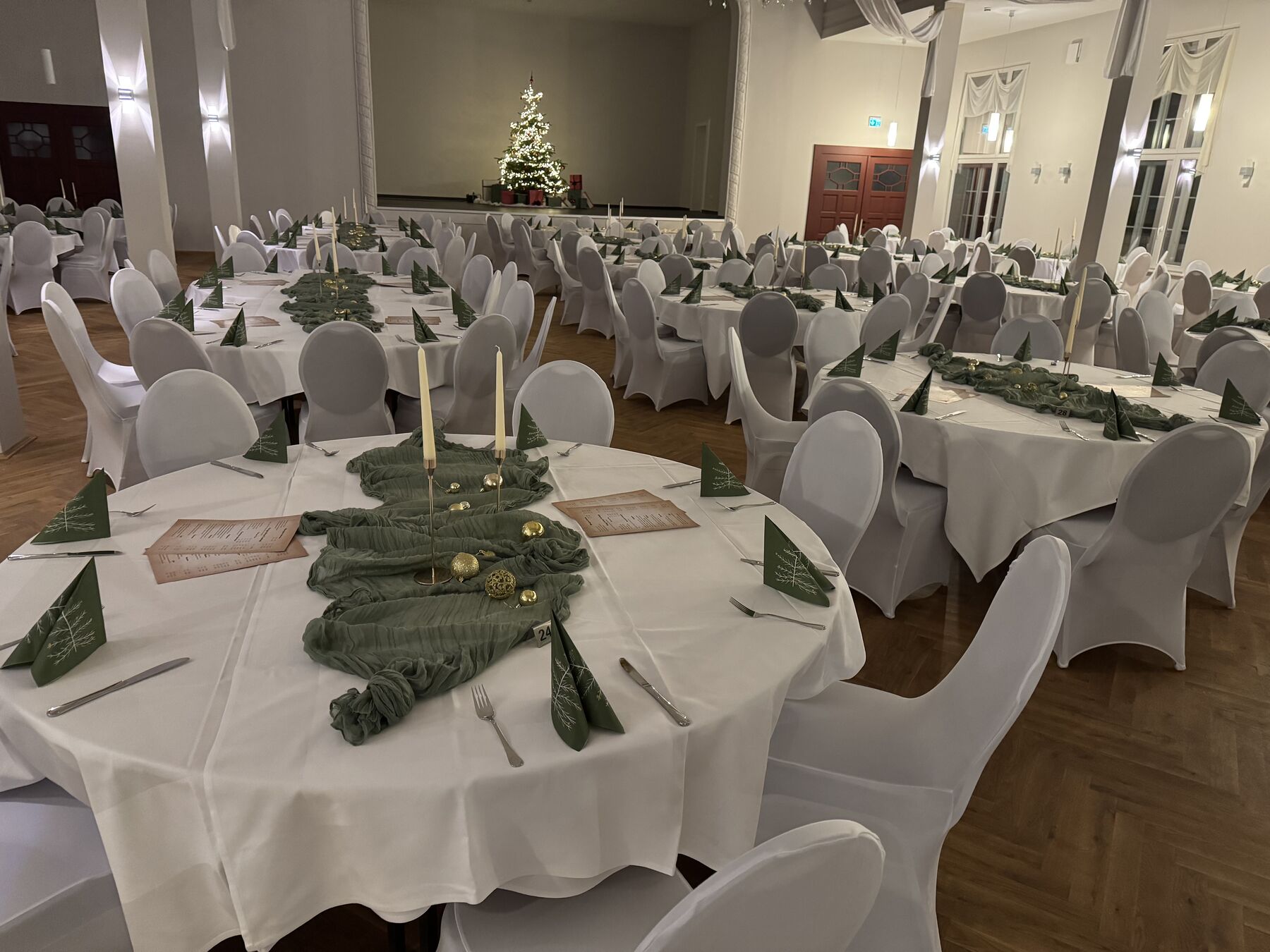 Saal zur Weihnachtsfeier mit Tannenbaum auf der Bühne