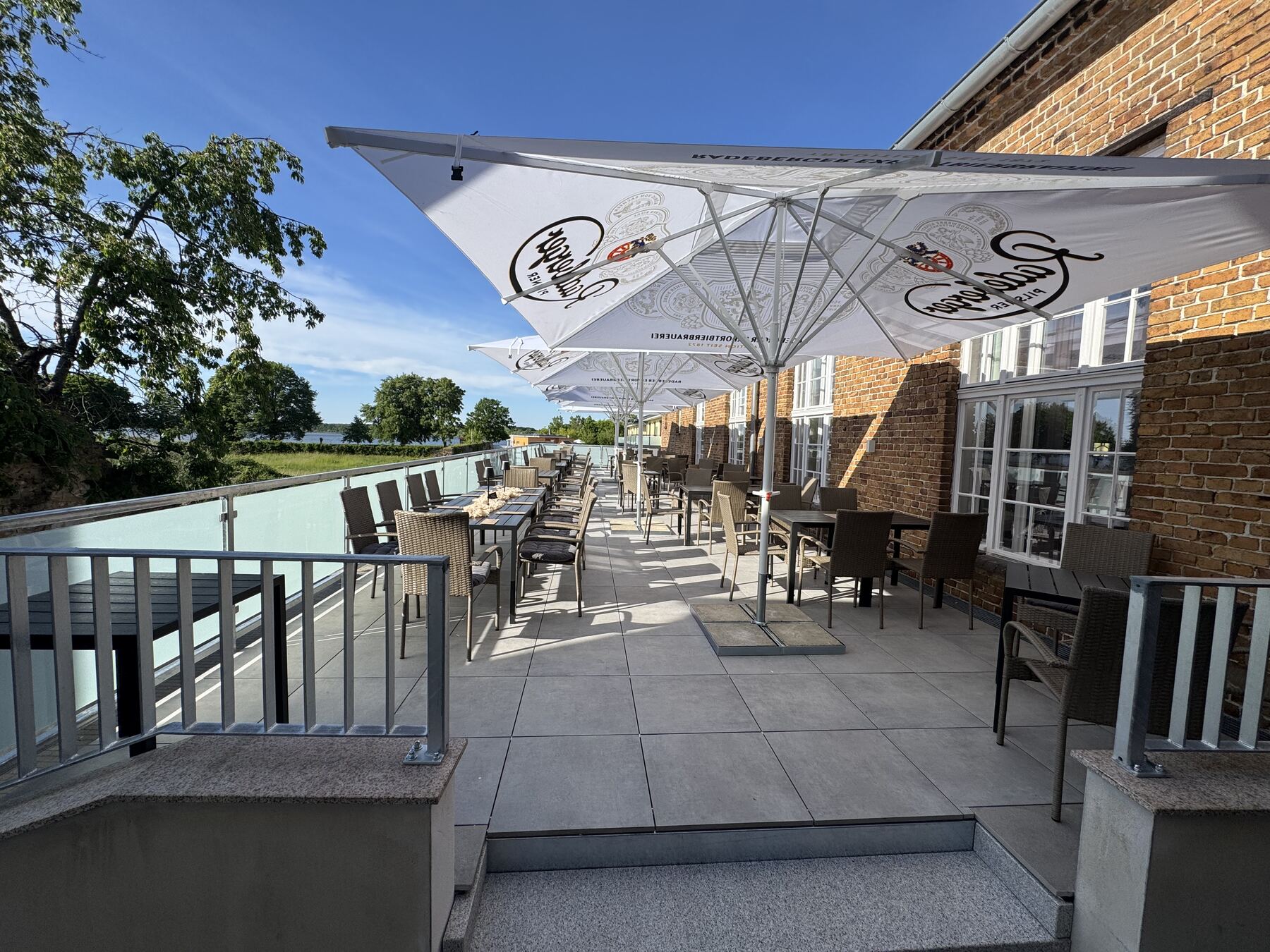 Terrasse des Dorfkrugs mit Tischen und Blick zum See