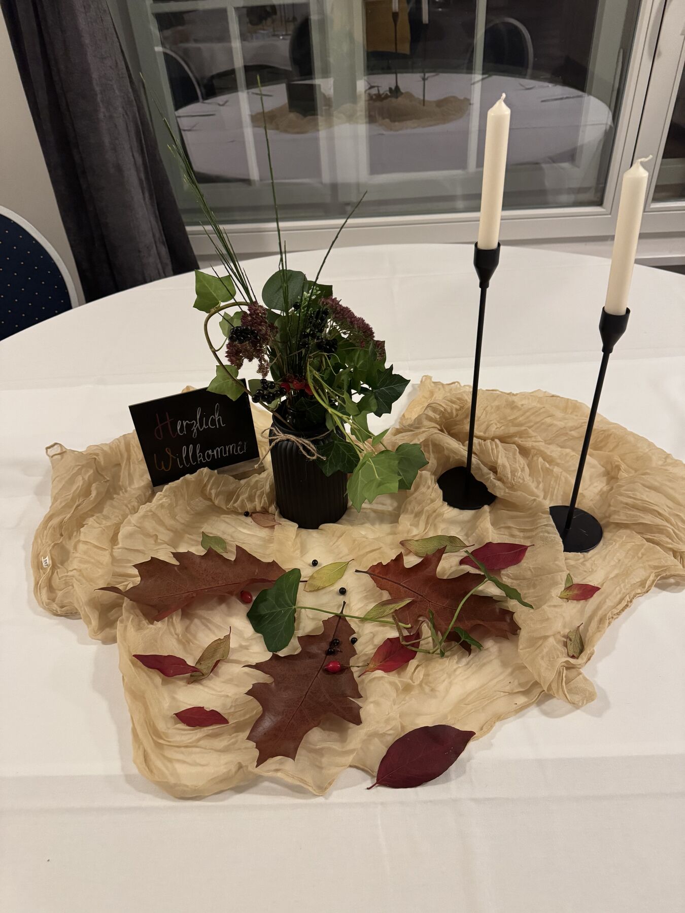Tischdekoration mit Herbstlaub und Kerzen